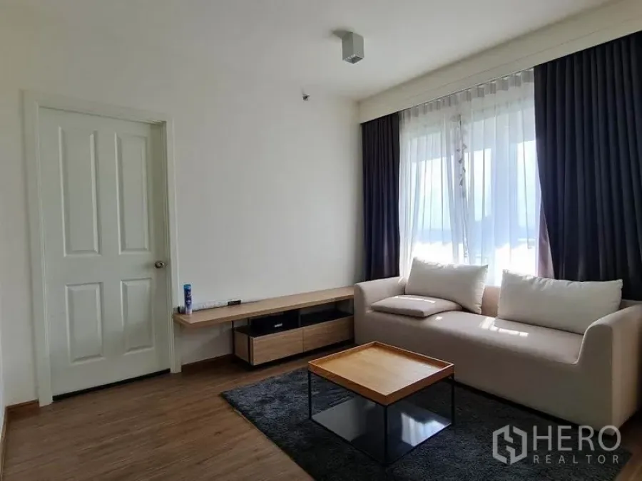 公寓 出租或出售在Yan Nawa, Bangkok - 明亮客厅设沙发、茶几、电视柜与大窗帘窗户。