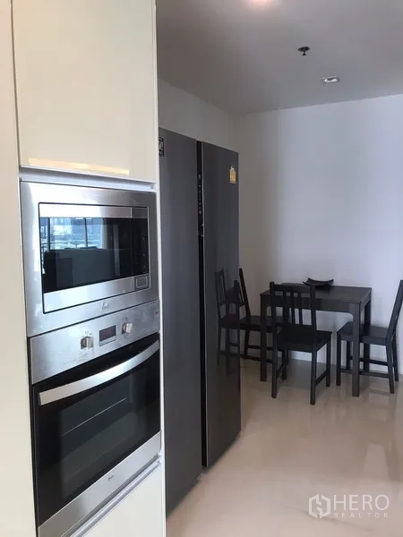 房间 出租在Khlong Toei, Bangkok - 厨房区配嵌入式烤箱、微波炉、大冰箱及小餐桌。