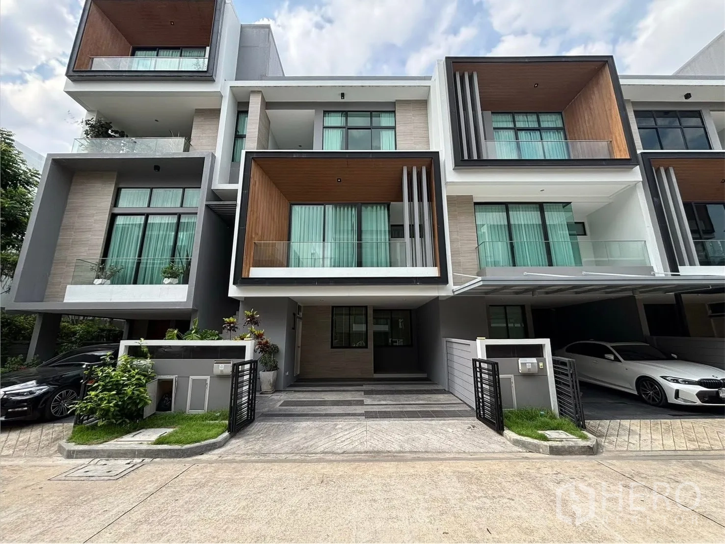 Townhouse for rent in Saphan Sung, Bangkok - Modern three-storey townhouse exterior with glass balconies and covered carports.