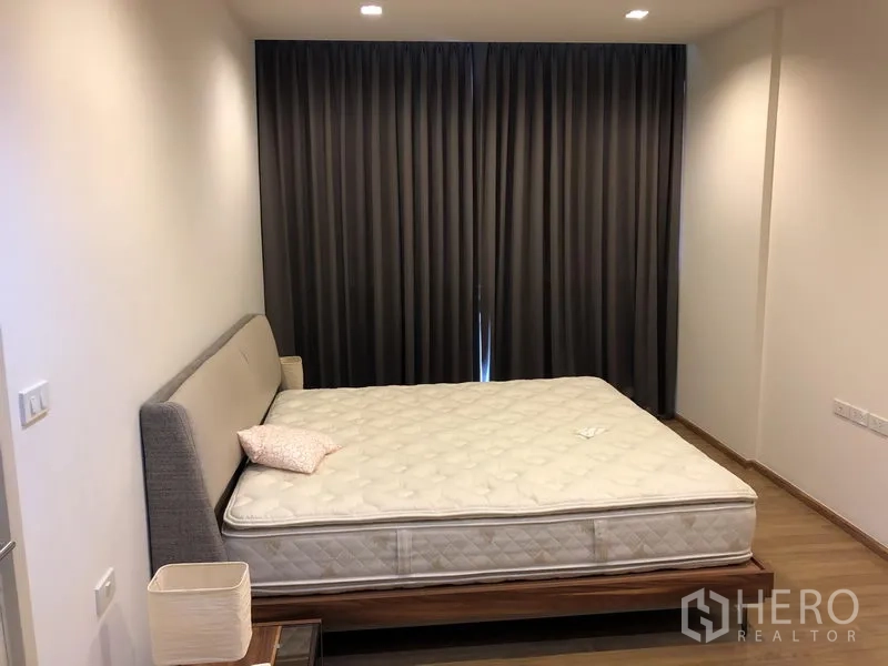 公寓 出租在Watthana, Bangkok - 宽敞主卧，特大床、木地板与遮光窗帘。