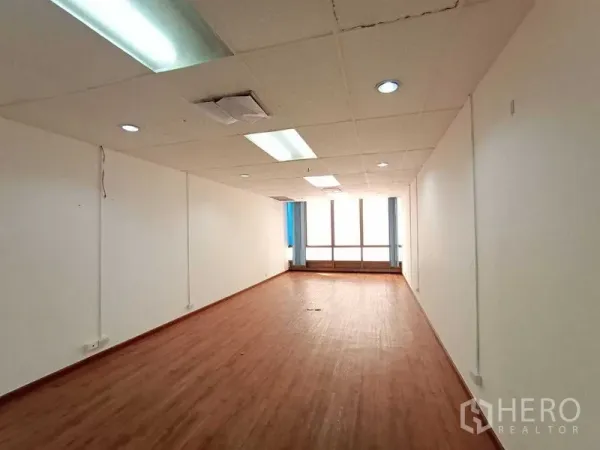 Office Space for rent - Long open-plan workspace with drop ceiling lights and a large window.