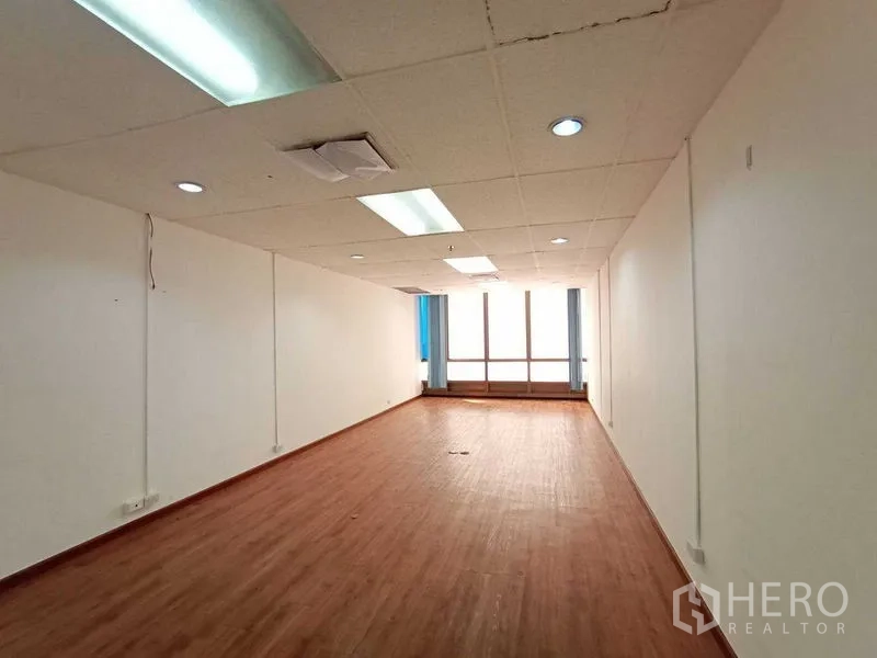 Office Space for rent - Long open-plan workspace with drop ceiling lights and a large window.