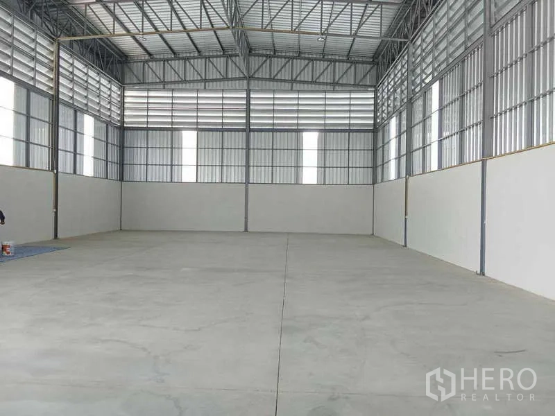 货栈 出租在Bang Bua Thong, Nonthaburi - 仓库内部空间，高挑钢结构屋顶，平整混凝土地面与透光采光带。