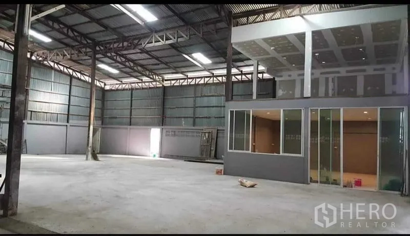 Warehouse for rent in Sai Noi, Nonthaburi - High‑ceiling warehouse interior with concrete floor and glass-fronted office