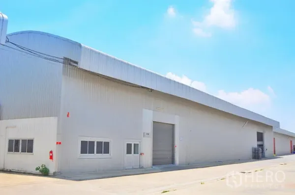 货栈 出租在Lat Krabang, Bangkok - 仓库侧立面，卷闸门、小型办公窗与消防设施