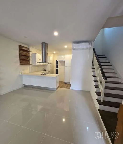 Townhouse for sale in Watthana, Bangkok - Open-plan living area with a white kitchen island and staircase.