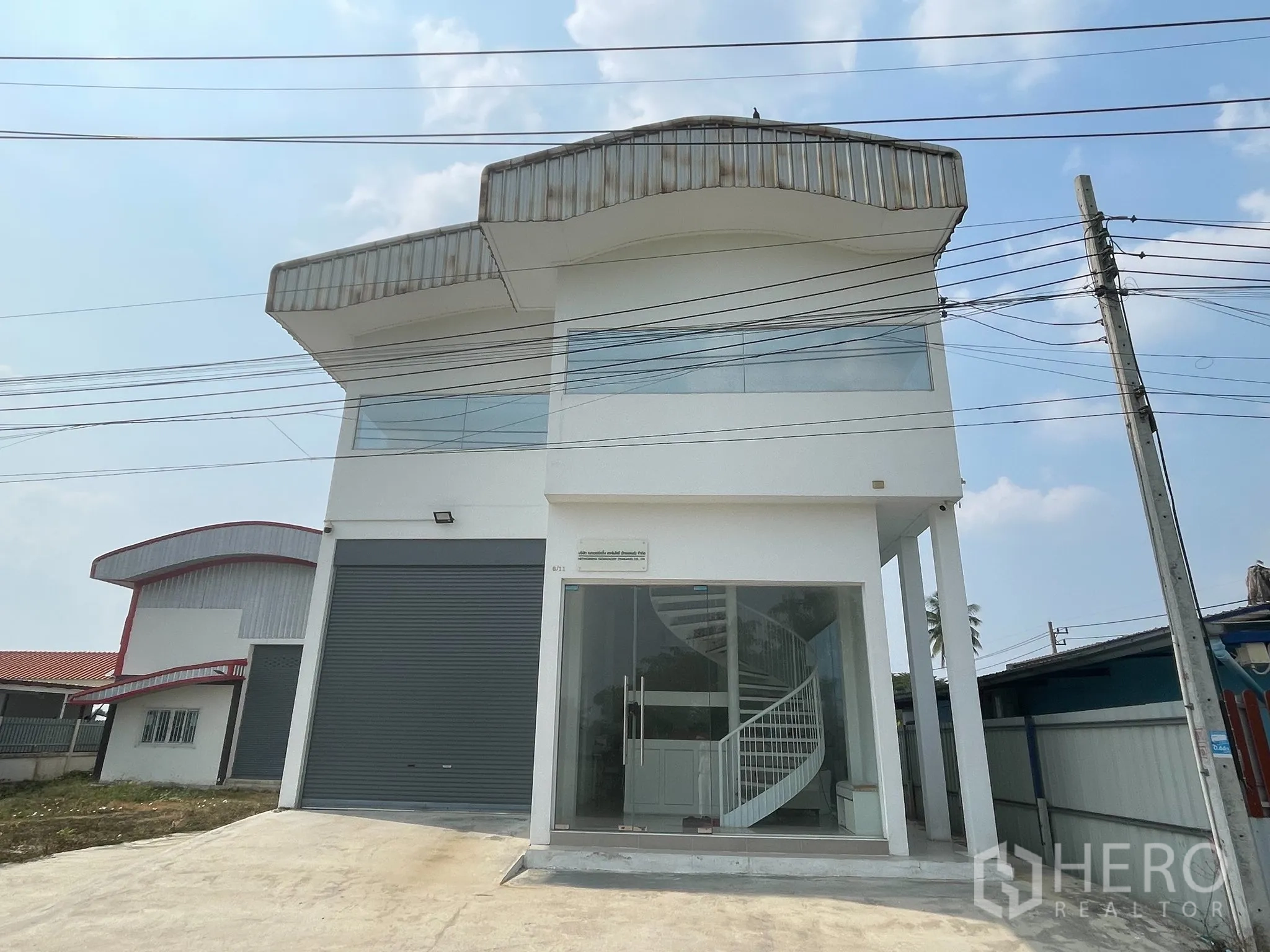 Warehouse for sale in Lat Lum Kaeo, Pathum Thani - Two-storey white warehouse with glass-fronted office, roller shutter door and wide driveway.