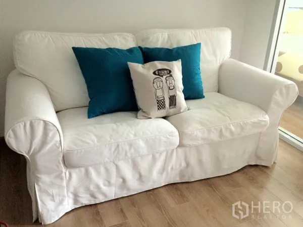 คอนโด ให้เช่าในKhlong Toei, Bangkok - โซฟาผ้าสีขาวสองที่นั่งพร้อมหมอนสีน้ำเงินบนพื้นไม้