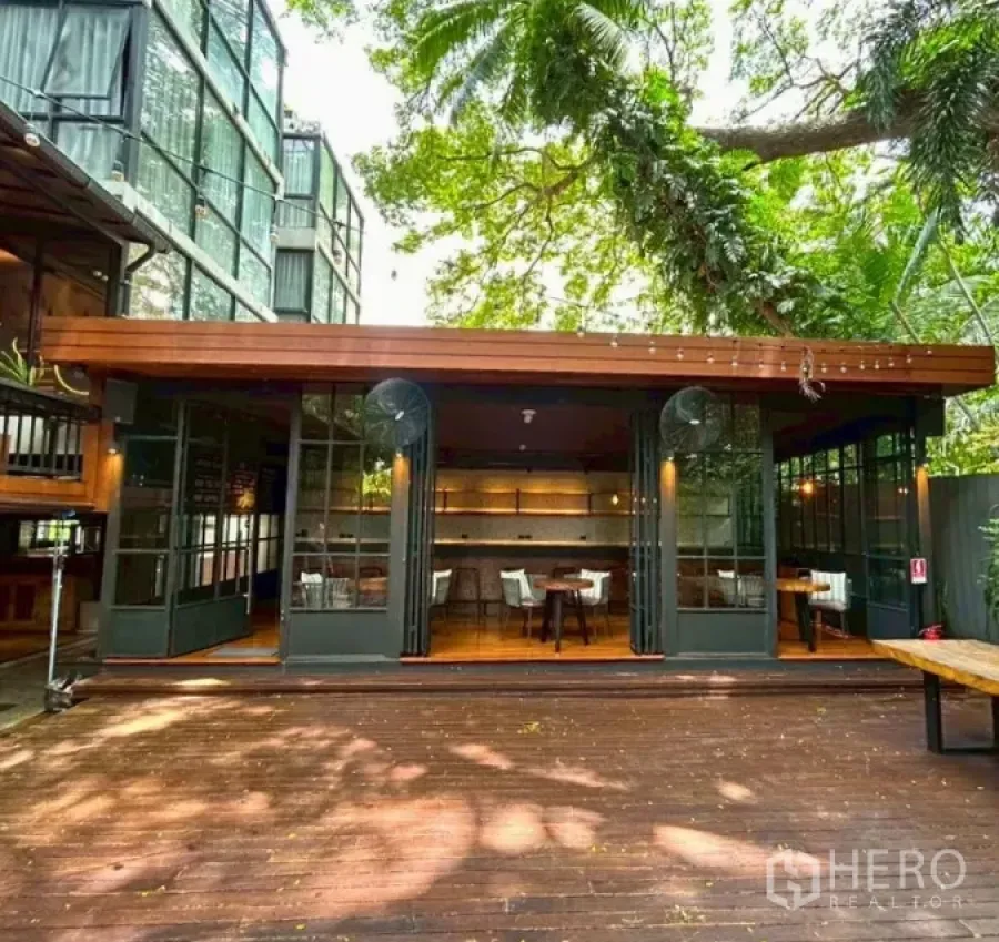 零售空间 出租在Yan Nawa, Bangkok - 绿荫庭院与可折叠玻璃门，连通木质露台的餐饮型门面。
