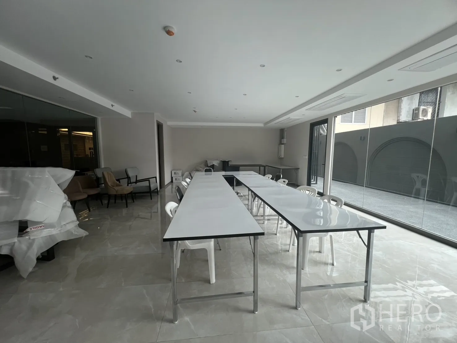 零售空间 出租在Watthana, Bangkok - 采光通透的开放式室内，亮面瓷砖地面、长桌与玻璃墙。