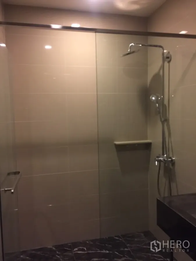 公寓 出租在Watthana, Bangkok - 现代浴室，玻璃淋浴间与顶喷花洒，深色石材台面。