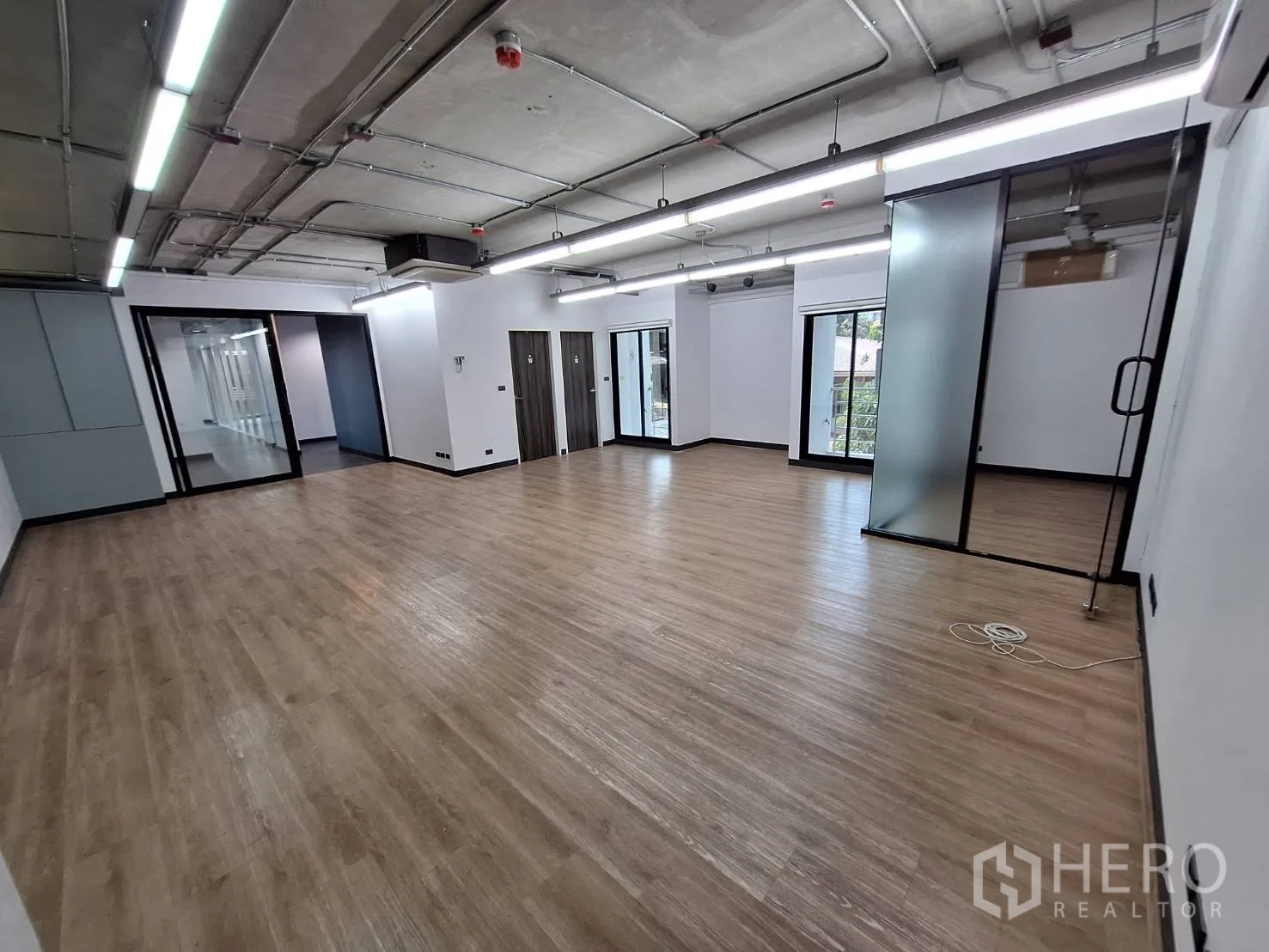 Office Space for rent - Work area featuring a frosted glass partitioned room and wood flooring.