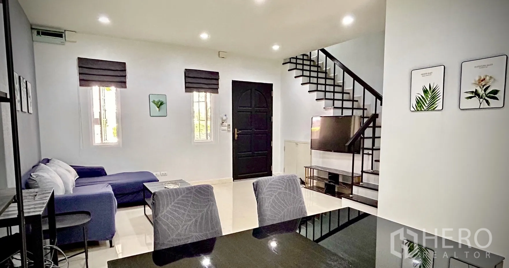 Townhouse for rent in Bang Kapi, Bangkok - Living room view toward the entrance and staircase with TV unit and modern black door.