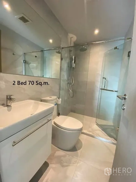Condominium for rent in Watthana, Bangkok - Contemporary bathroom with walk-in glass shower, vanity and modern tiling.