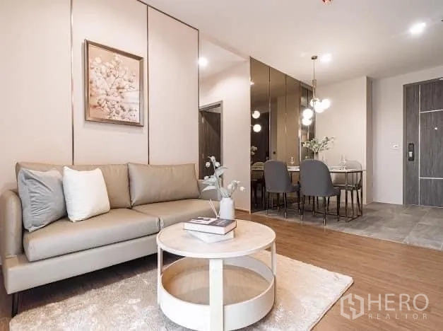 Condominium for rent in Watthana, Bangkok - Living room facing dining zone with mirrored feature wall.