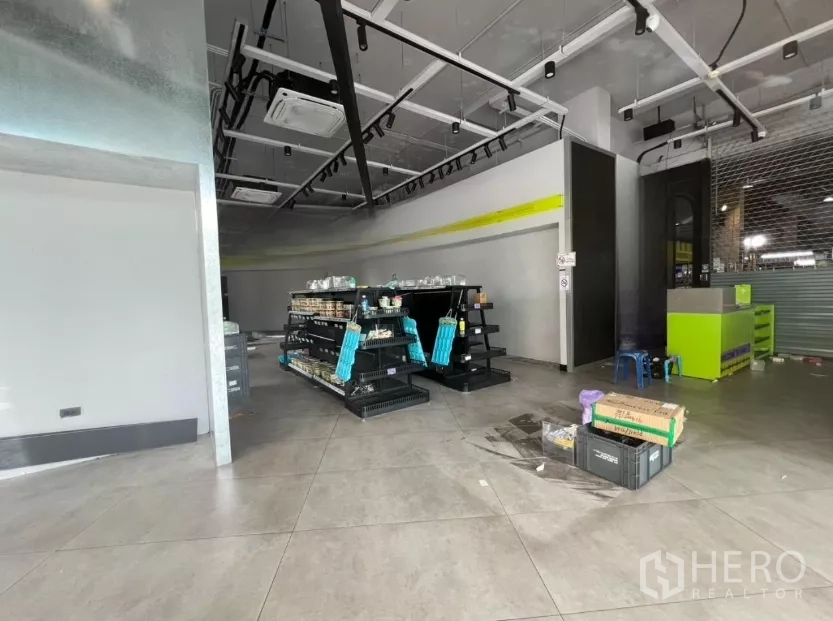 พื้นที่ขายปลีก ให้เช่า - พื้นที่ค้าปลีกมีชั้นวางสินค้า พื้นกระเบื้อง ไฟราง และเคาน์เตอร์บริการพร้อมใช้งาน.