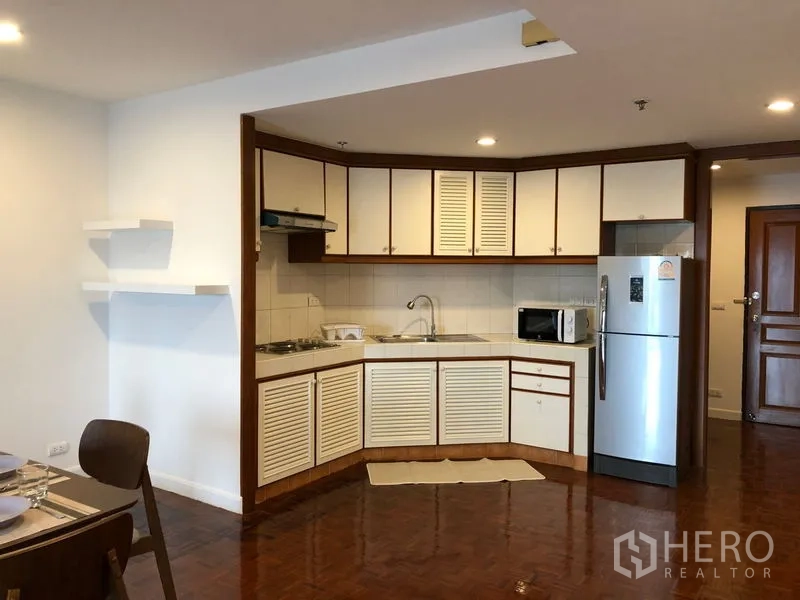 Condominium for rent or sale in Sathon, Bangkok - Open kitchen with L-shaped cabinets, stove, microwave and stainless refrigerator.