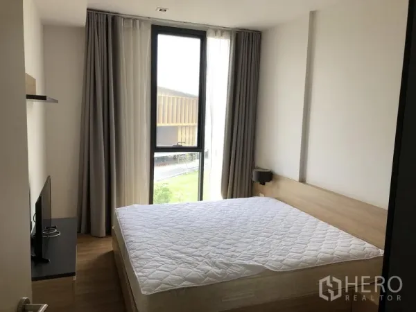 คอนโด ให้เช่าในWatthana, Bangkok - ห้องนอนหลักมีหน้าต่างบานใหญ่ เตียงนอน และวิวสวนเขียวพร้อมอาคารโดยรอบ