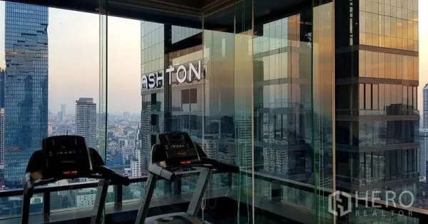 公寓 出售在Bang Rak, Bangkok - 高层玻璃健身房内的跑步机，可俯瞰城市全景。