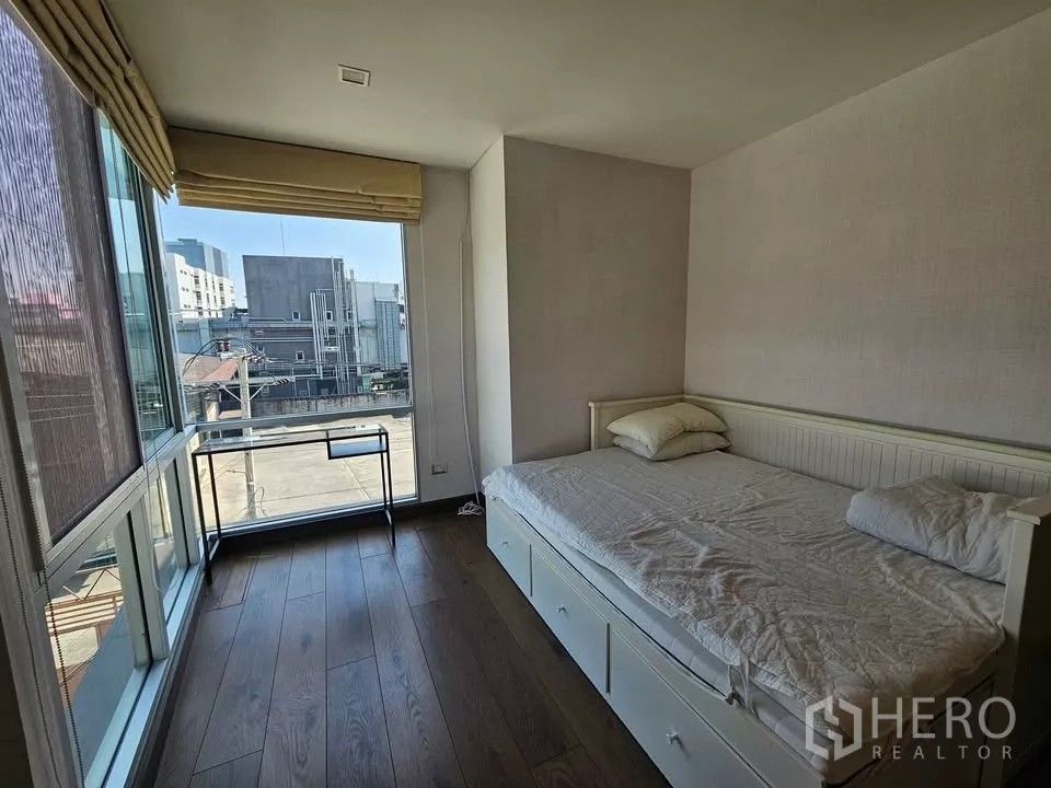 公寓 出售在Phra Khanong, Bangkok - 转角卧室，双面落地窗，日间床与书桌。