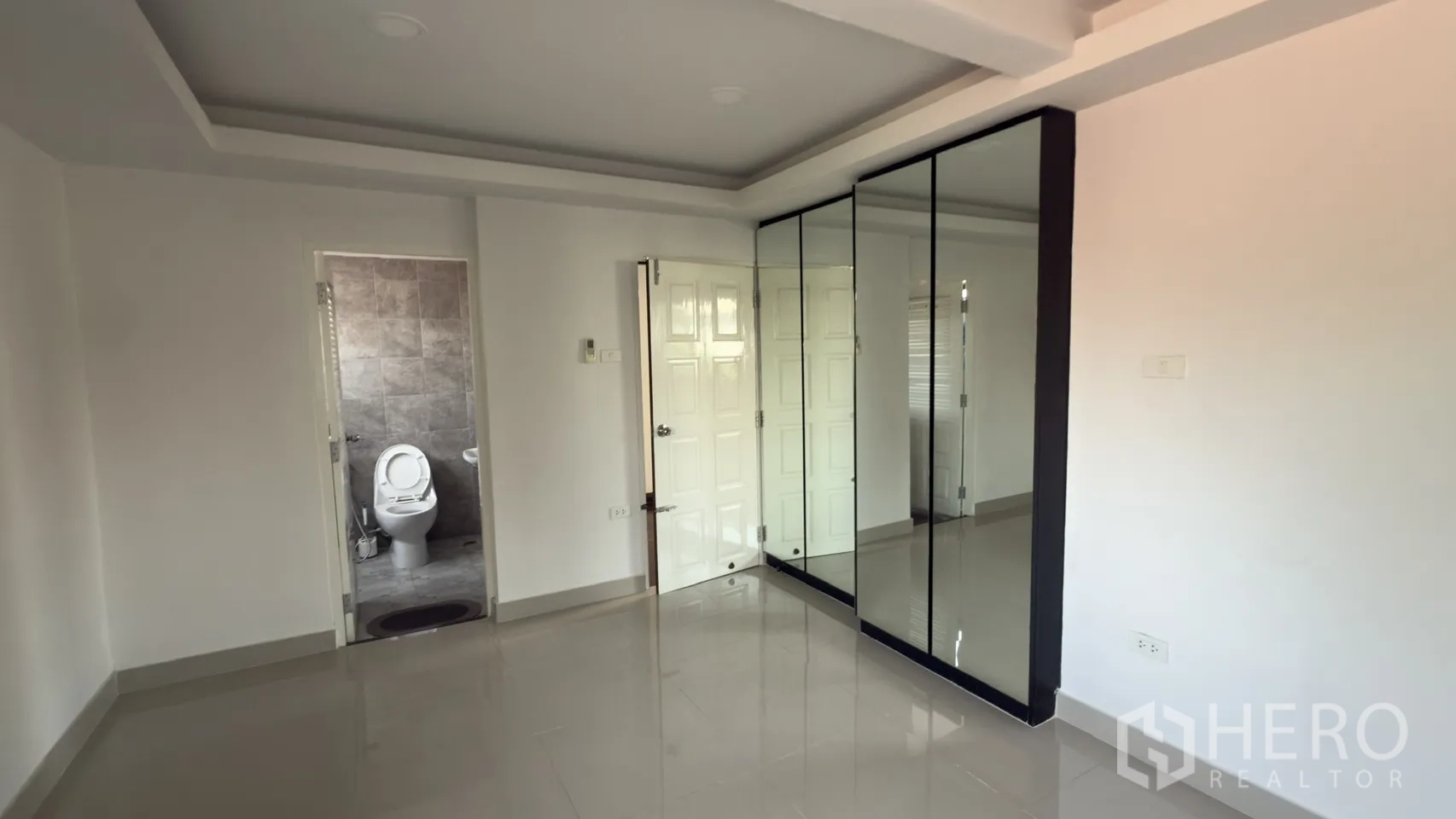 ทาวน์เฮาส์ for rent in Watthana, Bangkok - ห้องนอนพร้อมตู้เสื้อผ้าบานกระจกและห้องน้ำในตัวผนังกระเบื้องสีเทา