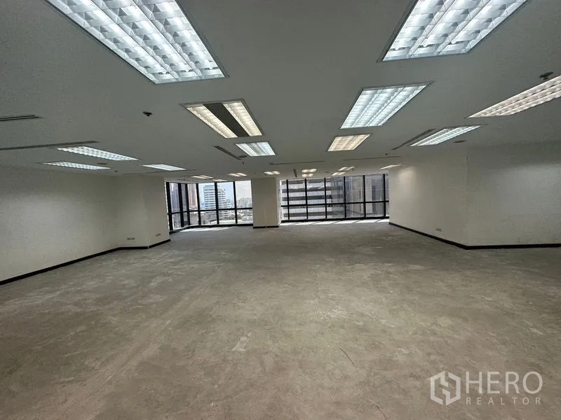Office Space for rent in Khlong Toei, Bangkok - Large open-plan office floor with drop-ceiling lights and wide windows at both ends.