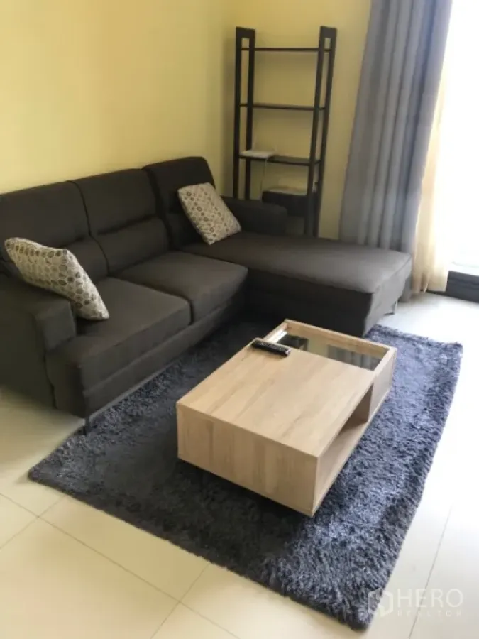 公寓 出租或出售在Khlong Toei, Bangkok - 客厅配L形沙发、长绒地毯与木质茶几，采光充足。