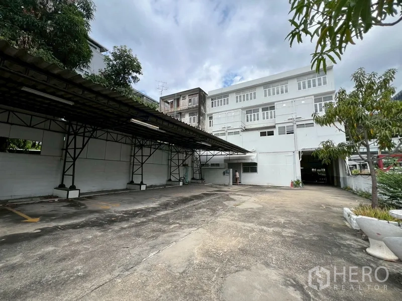 店屋 出租在Phra Khanong, Bangkok - 后院车场，带顶棚车位与建筑后立面。