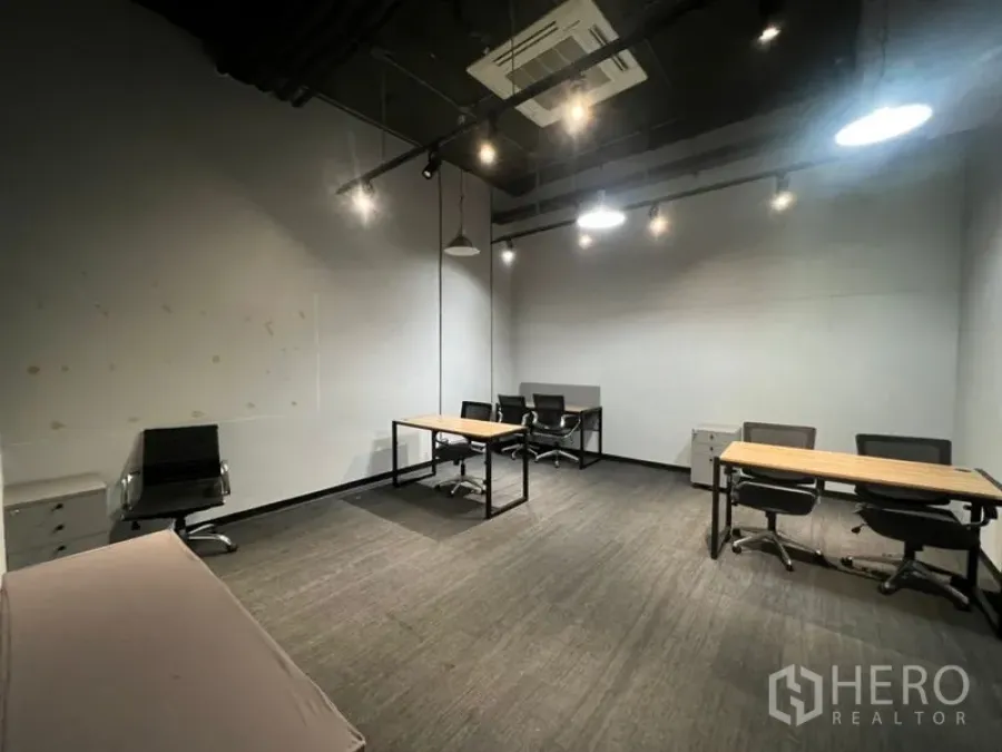 Office Space for rent - Modern private office with carpet flooring, high black ceiling, pendant and track lights, multiple desks and chairs.