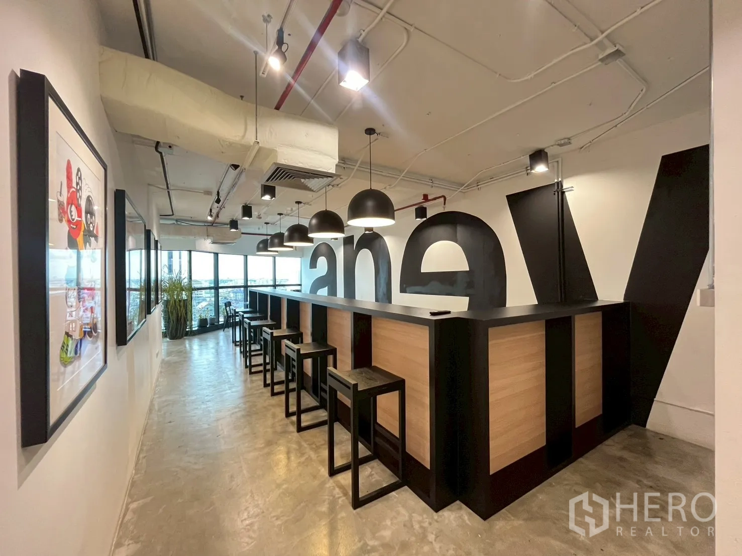 办公室 for rent in Watthana, Bangkok - 办公室走廊内的吧台式茶水区，配高脚凳与吊灯，临近大窗景观。