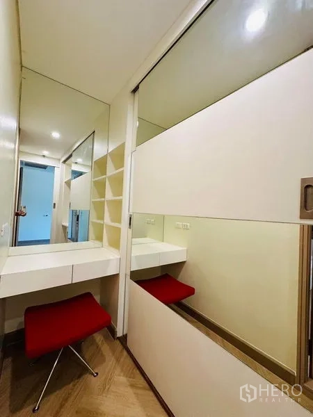 公寓 出租在Bang Rak, Bangkok - 走廊内的梳妆角，带镜面与搁架，配红色矮凳。