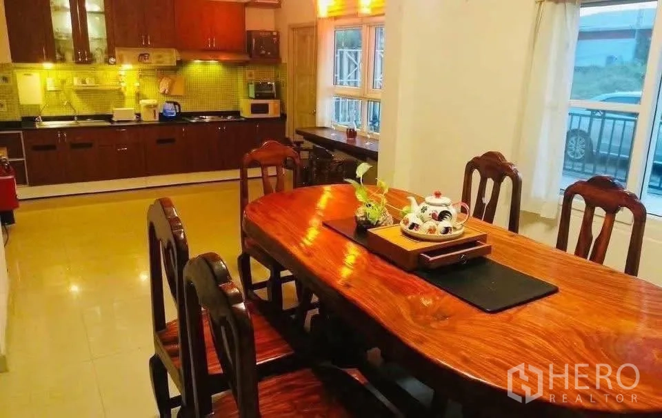 独立式住宅 出租或出售在Lam Luk Ka, Pathum Thani - 餐厅配实木餐桌，连接柜体齐全的开放式厨房。