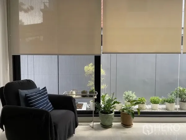 联排别墅 出售在Lat Phrao, Bangkok - 落地窗旁的阅读角，单人沙发与可见的盆栽景观。