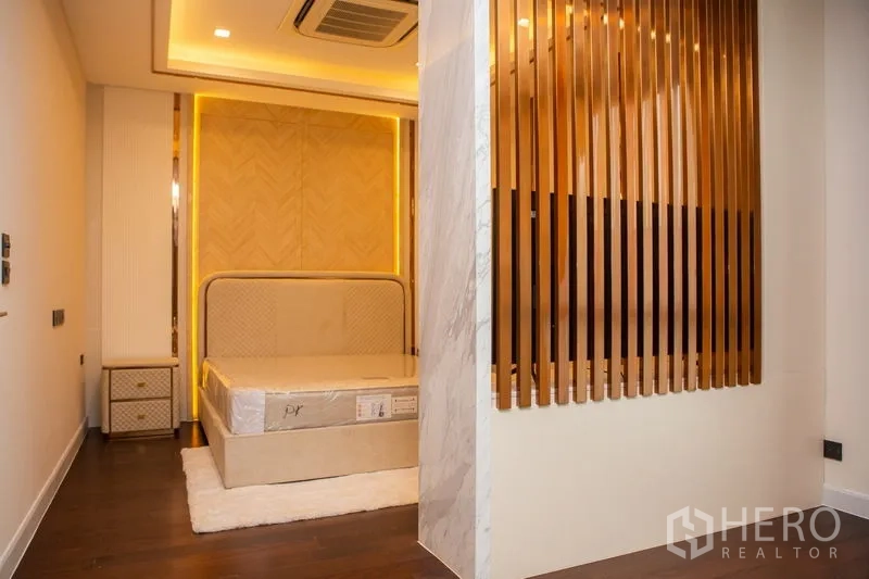 独立式住宅 出租或出售在Bangkok - 卧室设特色床头、天花嵌入式空调与金色格栅隔断。