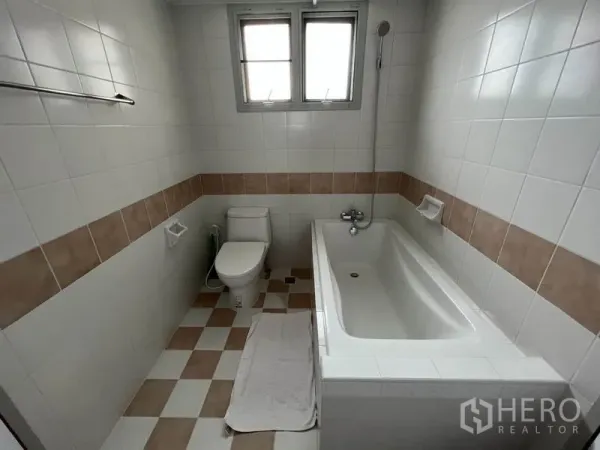 公寓 出租在Watthana, Bangkok - 浴室铺白色瓷砖和米色腰线，设浴缸、手持花洒与座厕。