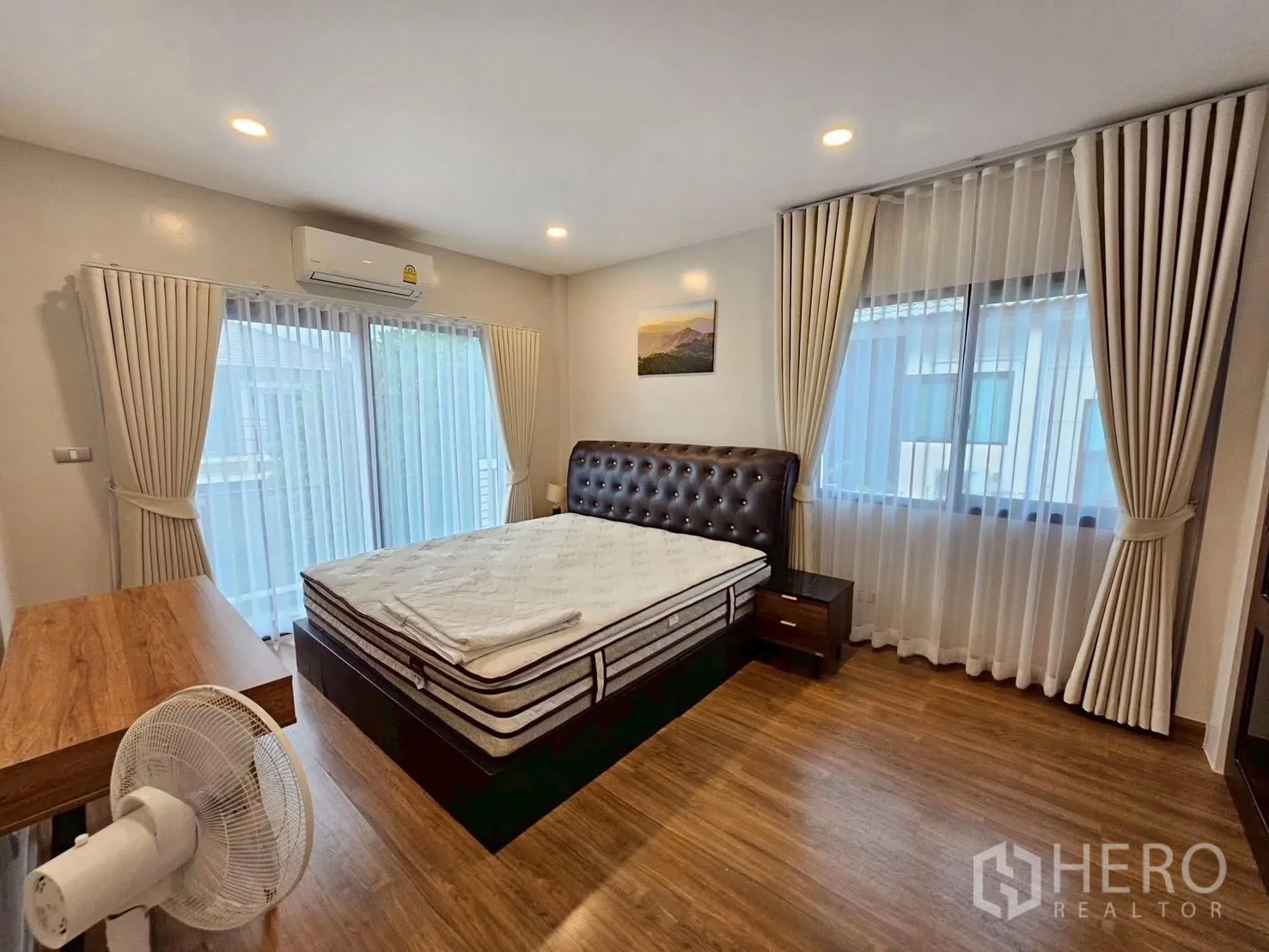 Detached House for sale in Bang Phli, Samut Prakan - Spacious master bedroom with sliding glass door to balcony, tufted headboard bed, double windows, and wood floors.