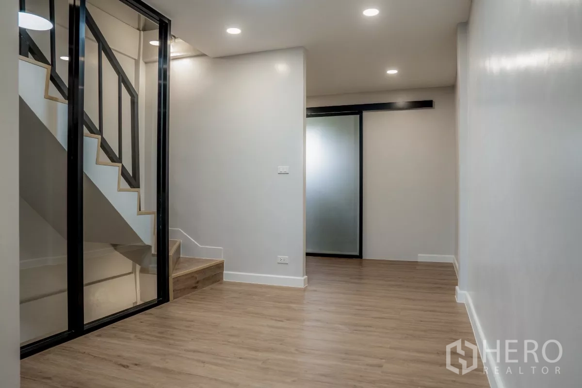 ทาวน์เฮาส์ ขายในWatthana, Bangkok - โถงทางเดินกั้นกระจกบันได ไฟดาวน์ไลท์ และพื้นไม้โทนอุ่น