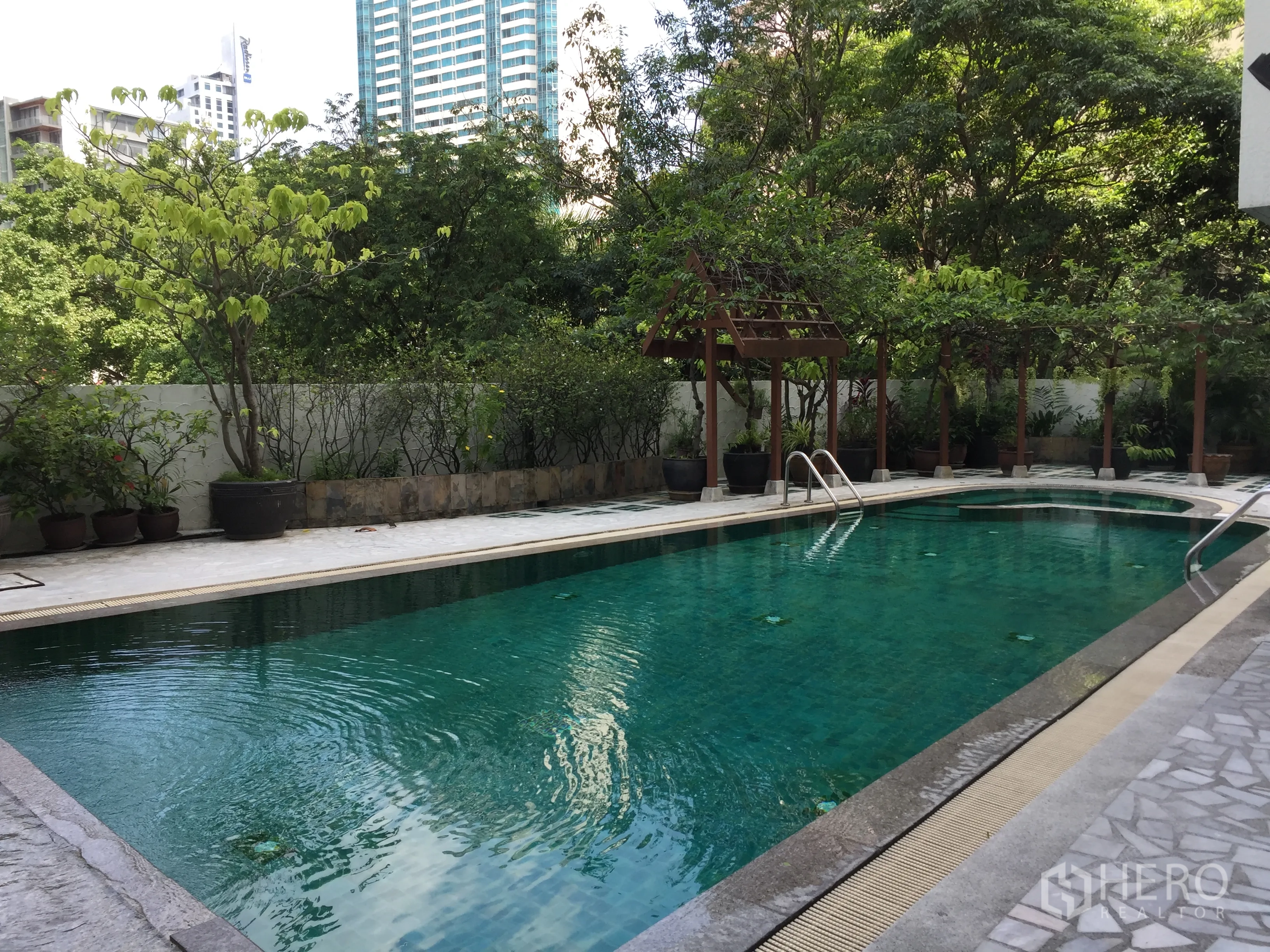 คอนโด ให้เช่าในKhlong Toei, Bangkok - สระว่ายน้ำกลางแจ้งของคอนโด รายล้อมด้วยต้นไม้และศาลาไม้ มองเห็นอาคารเมืองด้านหลัง