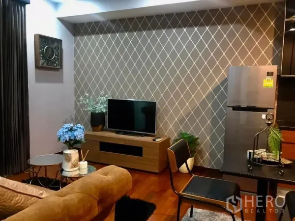 公寓 出租在Watthana, Bangkok - 舒适客厅，菱形纹理背景墙、电视柜与不锈钢冰箱。