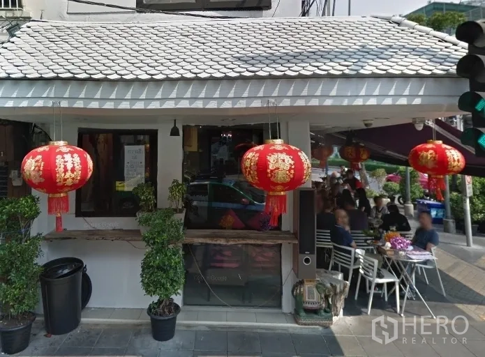 零售空间 出租在Bang Rak, Bangkok - 曼谷邦拉克转角商铺，白色外立面，悬挂红色灯笼，带户外座位。