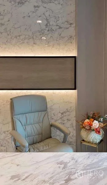 คอนโด ให้เช่าหรือขายในPathum Wan, Bangkok - เก้าอี้หนังใกล้ผนังตกแต่งหินอ่อนไฟซ่อน และแจกันดอกไม้