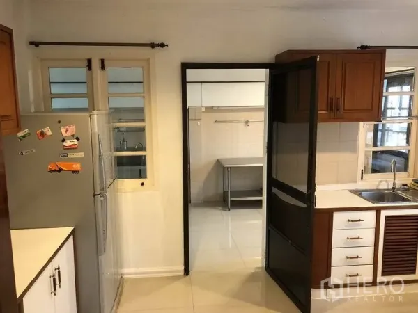 Detached House for rent - Fitted Western kitchen with wooden cabinets and sink, opening to a separate Thai kitchen.