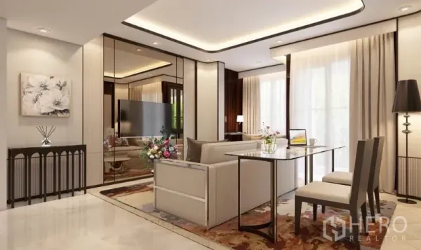 公寓 出租在Watthana, Bangkok - 开放式起居区，米色沙发、镜面墙、电视以及靠窗的双人餐桌。