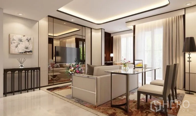 公寓 出租在Watthana, Bangkok - 开放式起居区，米色沙发、镜面墙、电视以及靠窗的双人餐桌。