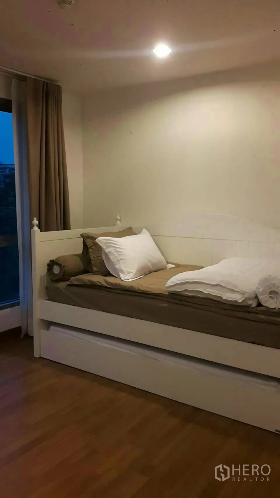 คอนโด ให้เช่าในPhaya Thai, Bangkok - ห้องนอนเล็กพร้อมเตียงเดย์เบดสีขาว พื้นไม้ และหน้าต่างบานใหญ่พร้อมผ้าม่าน