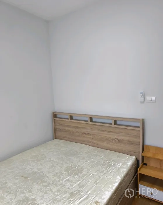 Townhouse for rent in Bang Phli, Samut Prakan - Bed with wooden headboard and a small bedside shelf against a white wall.