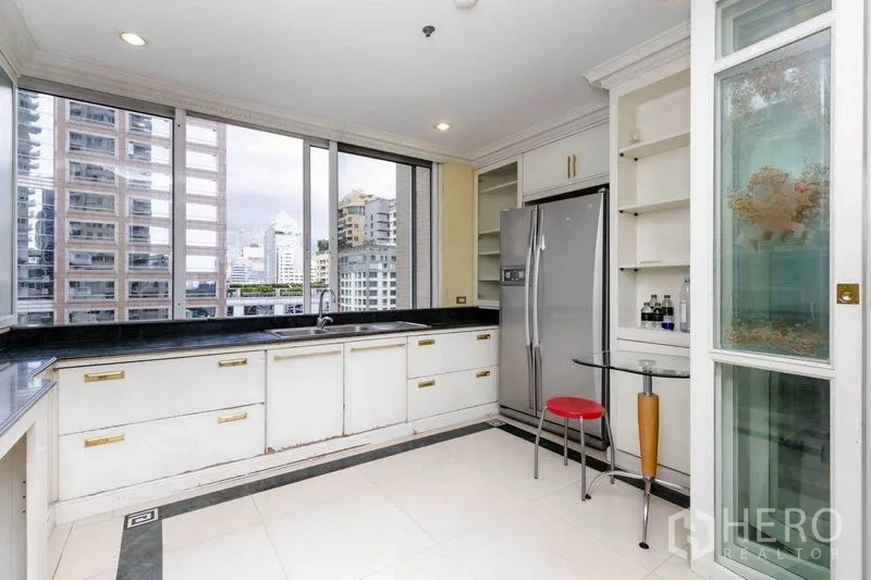 Condominium for rent or sale in Pathum Wan, Bangkok - Corner kitchen with black stone countertops, white cabinets, and city skyline views.