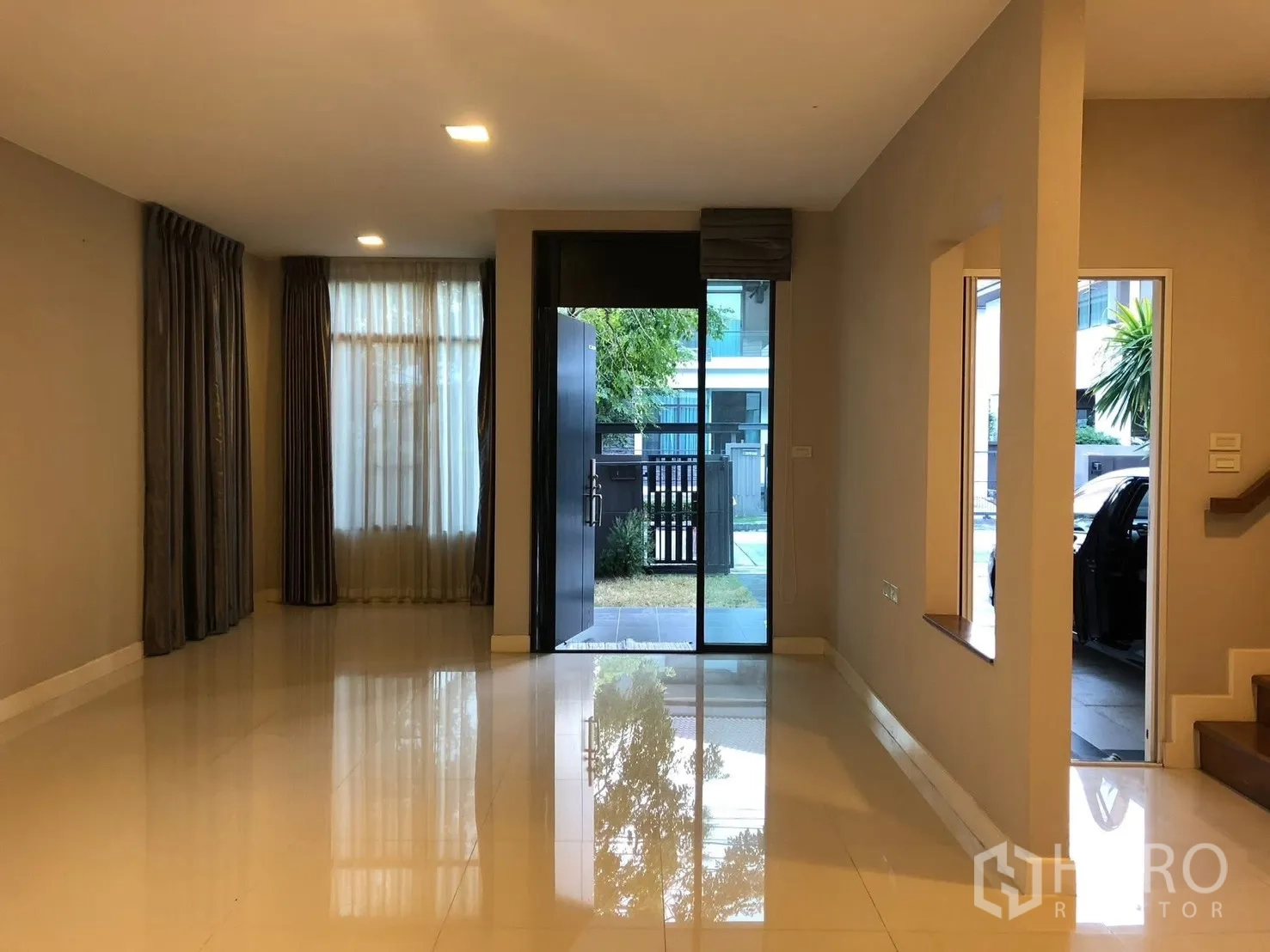 บ้านเดี่ยว for rent in Prawet, Bangkok - ห้องนั่งเล่นสว่างพื้นกระเบื้องเงา หน้าต่างบานใหญ่ และประตูหน้าบ้านเปิดสู่สวนเล็ก