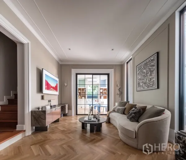 บ้าน ให้เช่าหรือขายในPhra Khanong, Bangkok - ห้องนั่งเล่นโทนอบอุ่น พื้นไม้ก้างปลา ประตูกระจกเชื่อมห้องทำงาน