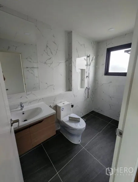 Detached House for rent in Bang Phli, Samut Prakan - Contemporary bathroom with marble-look wall tiles, vanity, toilet and window.